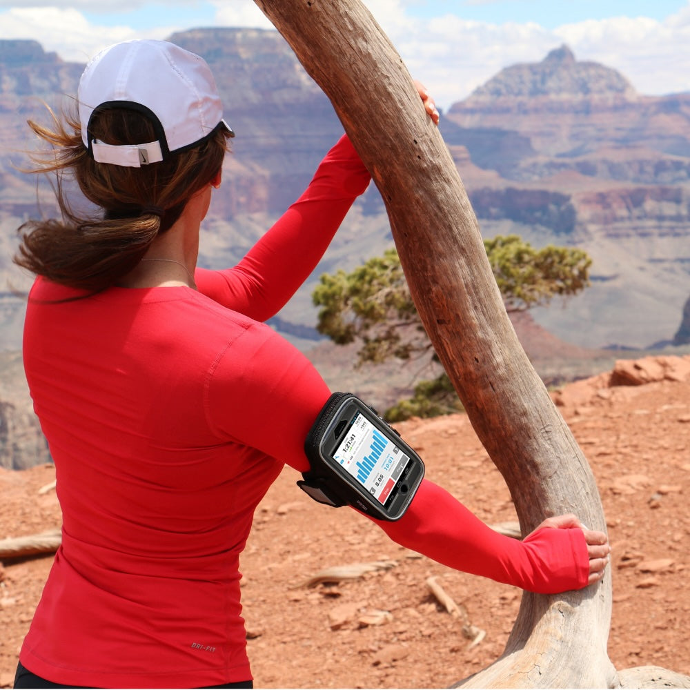 Woman hiking with Sporteer performance armband for iPhone and Galaxy on her arm, overlooking the Grand Canyon.