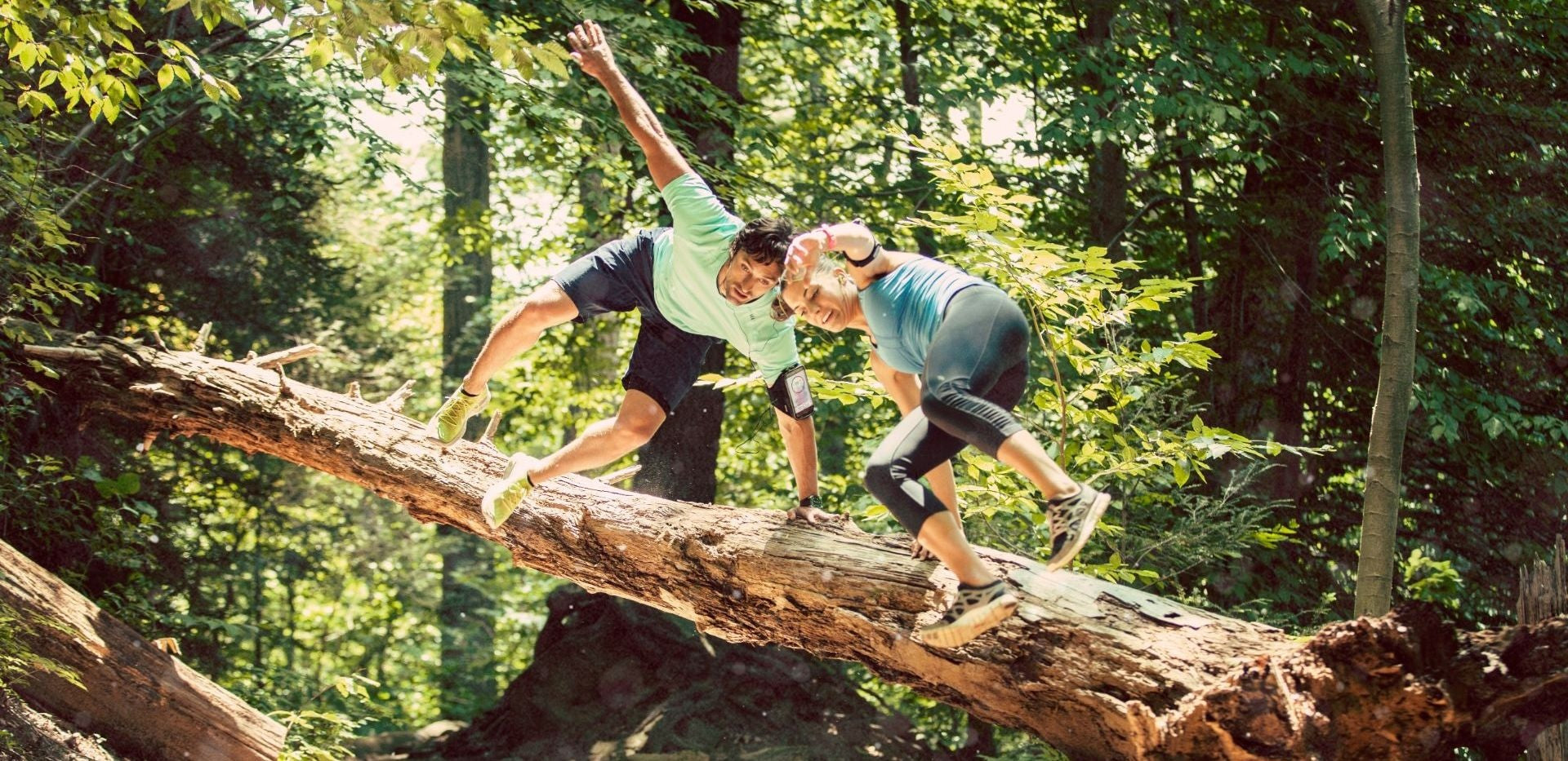 Two athletes in mid-motion wearing Sporteer performance armbands to demonstrate bounce-free security and uninterrupted movement.