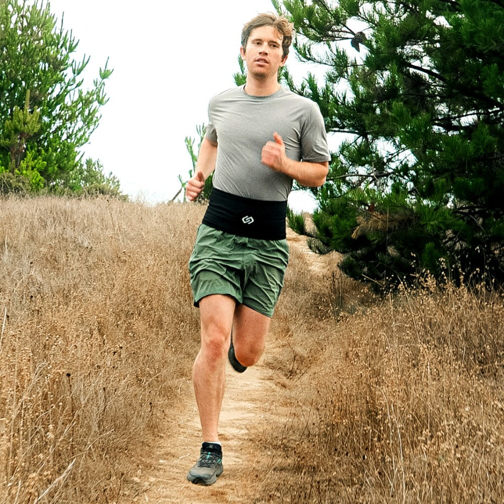 Male trail runner wearing a black Sporteer VersaBelt, demonstrating a bounce-free and secure fit for mobile tech.